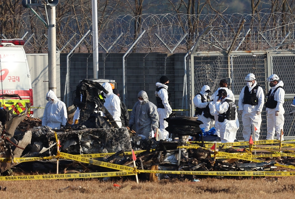 Officials at the site where the Jeju Air Boeing 737-800 aircraft crashed and burst into flames at Muan International Airport. — AFP
