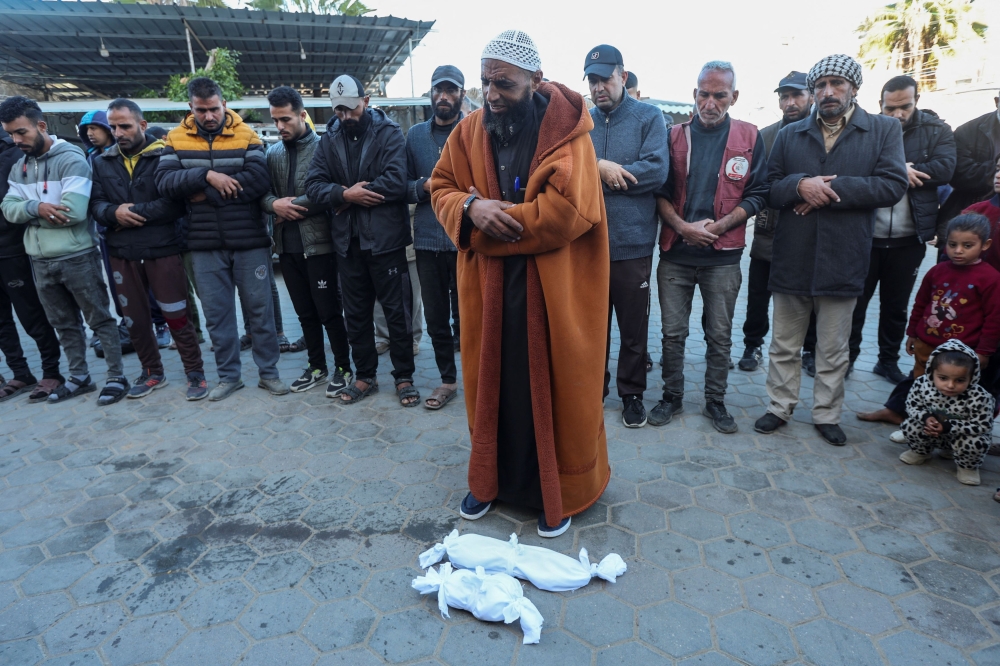 People pray next to the bodies of two Palestinian babies, including infant Jumaa Al-Batran, who died of hypothermia after living in a tent with his displaced family, at Al-Aqsa Martyrs Hospital in Deir Al-Balah in the central Gaza Strip, December 29, 2024. — AFP pic