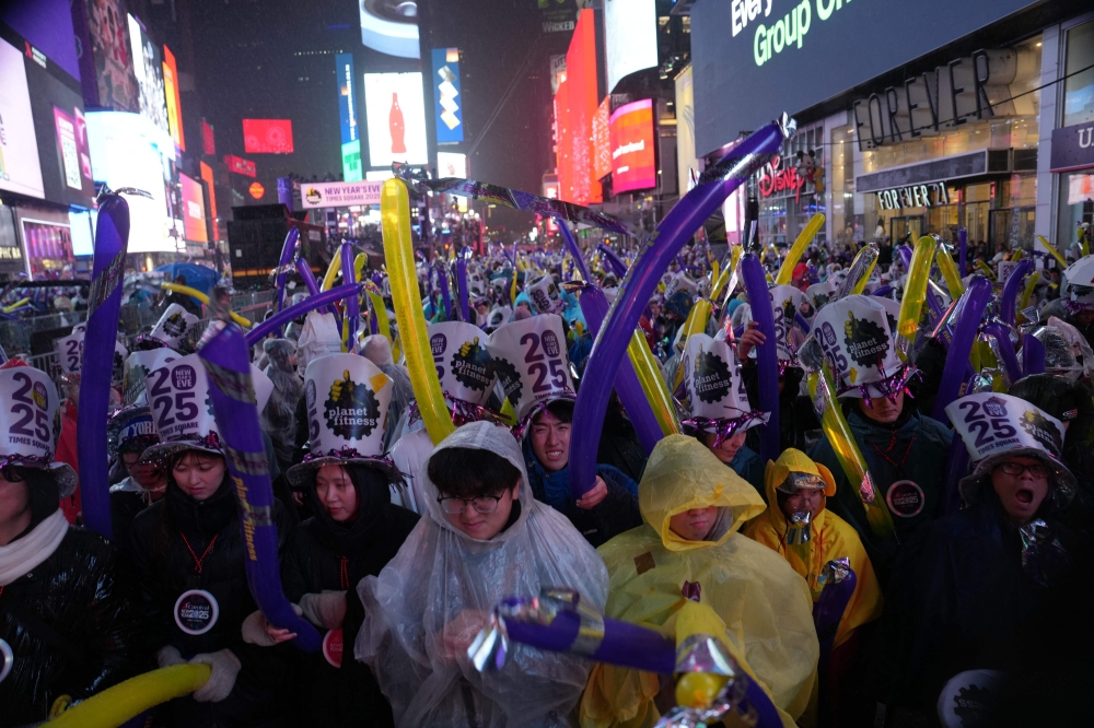 Revelers wait in the rain at Times Square for the midnight ball drop for the New Year's Eve celebration on December 31, 2024 in New York City. — AFP pic