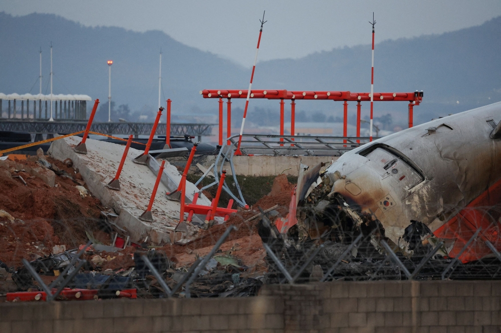 The wreckage of the Jeju Air aircraft that went off the runway and crashed at Muan International Airport lies near a concrete structure it crashed into, in Muan, South Korea. — Reuters