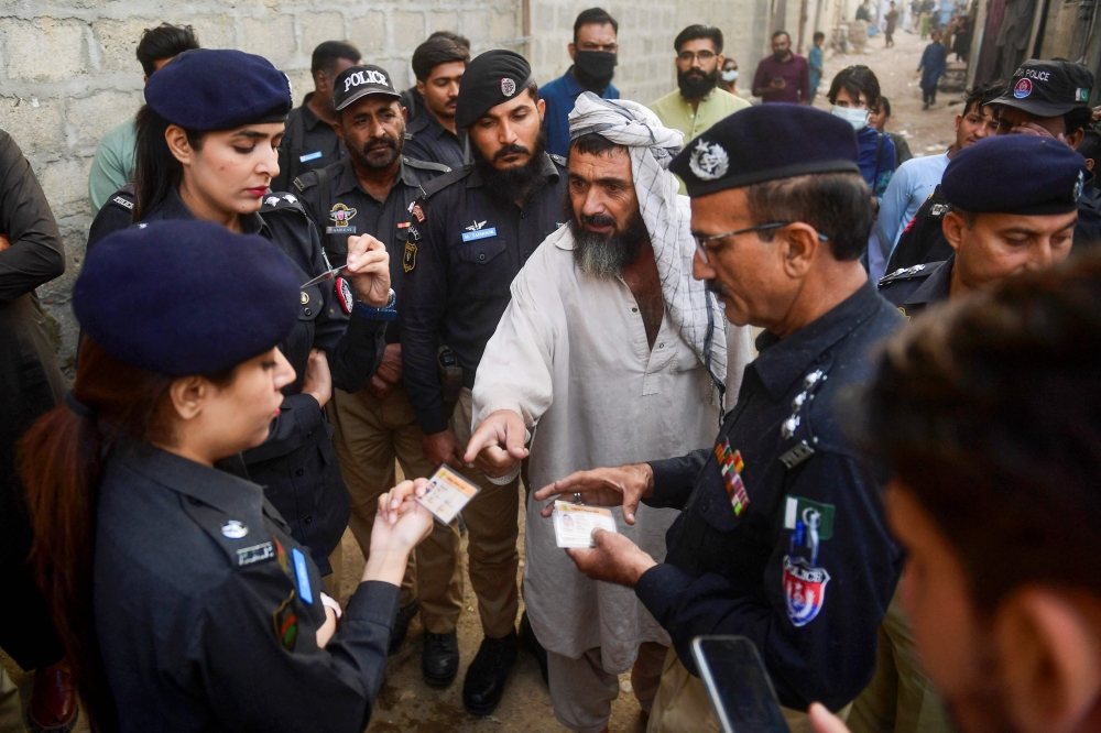Pakistani police check documents of Afghan refugees during a search operation to identify alleged illegal immigrants on the outskirts of Karachi. — AFP pic