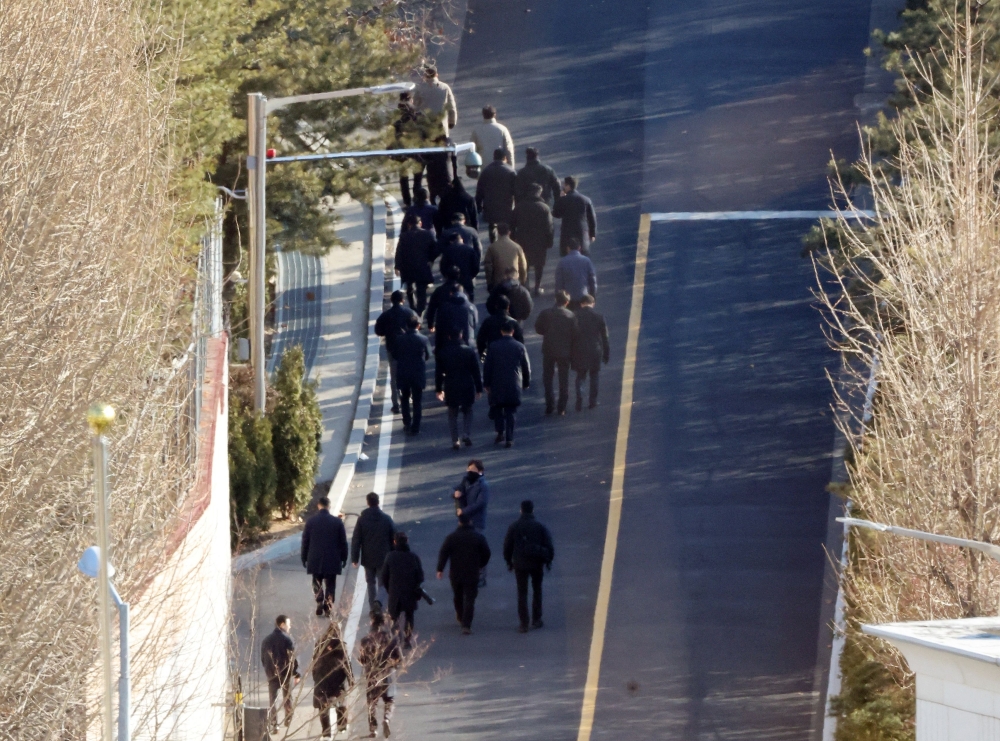 Anti-corruption investigators walk up a hill inside the presidential residence of impeached South Korea President Yoon Suk-yeol in Seoul January 3, 2025. South Korean investigators attempted to arrest impeached President Yoon at his residence on January 3 over a failed martial law bid, but security forces were blocking their efforts. — Yonhap/AFP pic