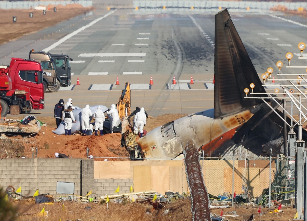 Investigators from South Korea and the US inspect the scene of the Jeju Air passenger plane crash at Muan International Airport in Muan January 3, 2025. — Yonhap/AFP pic