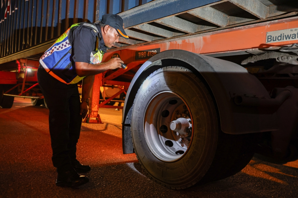 Road Transport Department (JPJ) personnel conduct a tyre tread inspection on heavy vehicles during a Special Motorcycle Operation at Awan Besar Toll Plaza on the Shah Alam Highway January 1, 2025. — Bernama pic