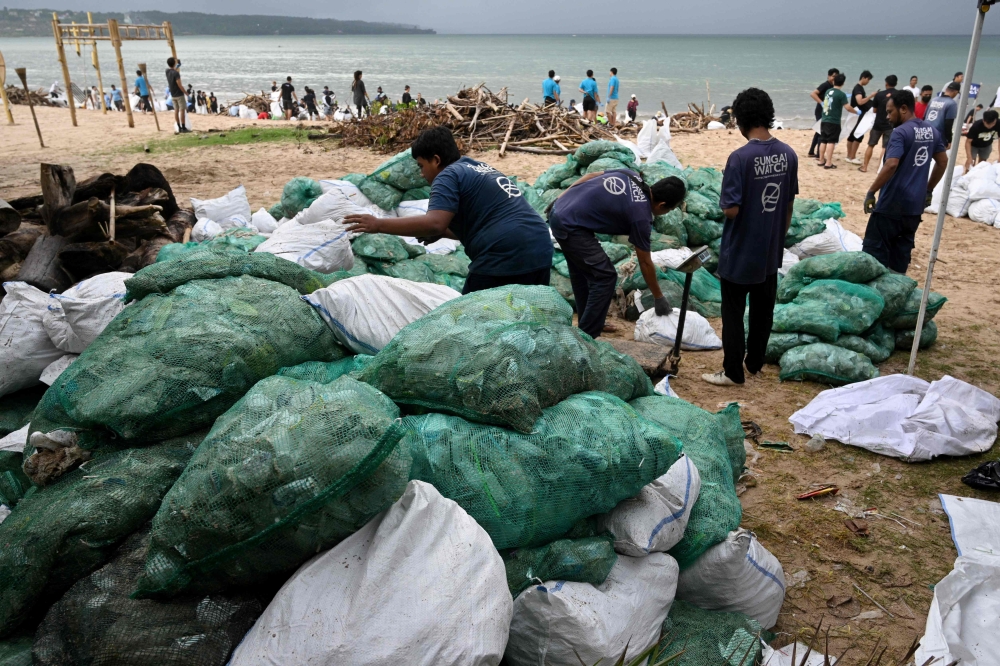 Participants and volunteers remove plastic waste and other garbage washed ashore at a beach in Kedonganan Badung regency, Indonesia's Bali island on January 4, 2025. — AFP pic