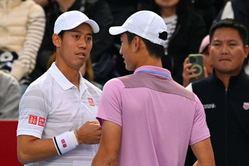 China's Shang Juncheng (right) informs Japan's Kei Nishikori that he is retiring with illness from their men's singles semi-final match at the Hong Kong Open tennis tournament in Hong Kong on January 4, 2025. — AFP pic