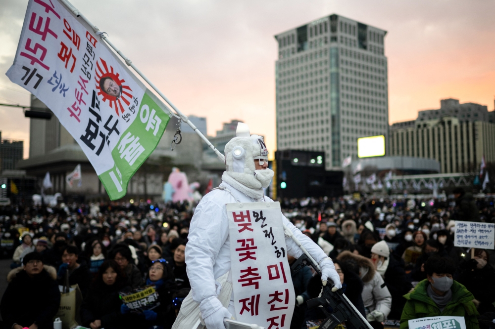 An anti-Japan activist carrying a flag with the portrait of impeached South Korea's president Yoon Suk Yeol takes part in a rally to protest against him in front of the Gwanghwamun Gate in Seoul. — AFP