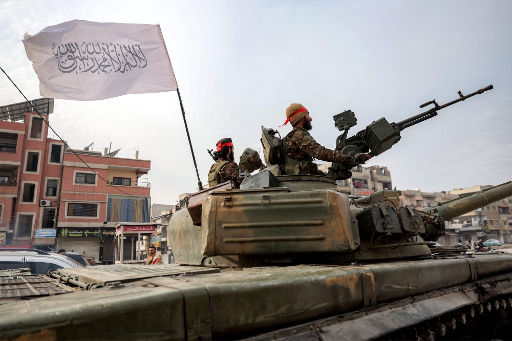 An Islamic flag bearing the Shahadah (Muslim creed) flies from a tank used by fighters loyal to the interim Syrian government in Homs on January 4, 2025. — AFP pic