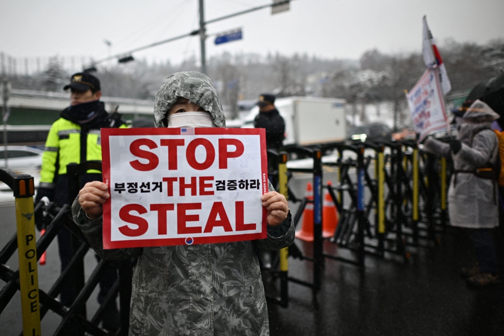 A supporter of impeached South Korea President Yoon Suk Yeol standing near a police barricade during a rally near Yoon's residence as snow falls in Seoul. — AFP