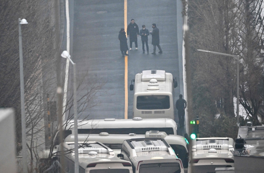 Security personnel walk on the road with buses blocking an entrance gate to protect impeached South Korean President Yoon Suk Yeol from a possible second arrest attempt. — AFP