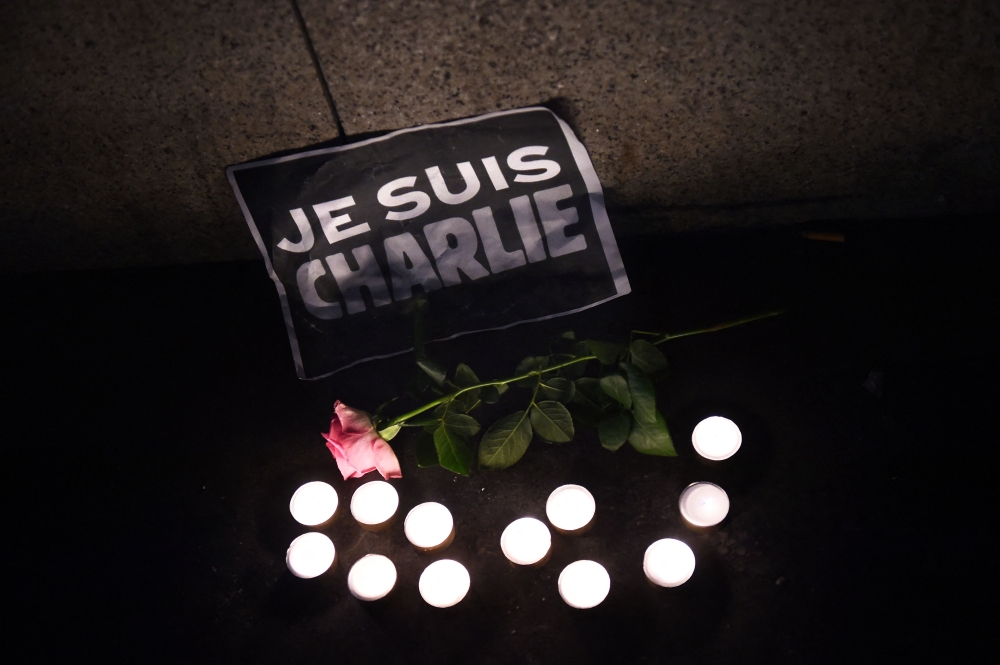 File photo of candles, a rose and a sign that reads in French, ‘I am Charlie’ placed on the ground as people hold a candle lit vigil at the Old Harbour in Marseille, on January 7, 2015. — AFP