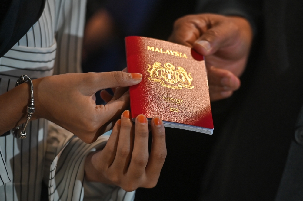 People hold a Malaysian passport at the Immigration Department in Putrajaya on Feb 19, 2024. — Picture by Miera Zulyana