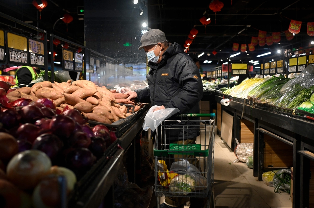 An elderly man selects vegetables at a supermarket in Beijing on January 9, 2025. Sluggish spending — combined with persistent woes in the property sector and local government financing strains — has cast doubt on the feasibility of official growth targets. — AFP pic