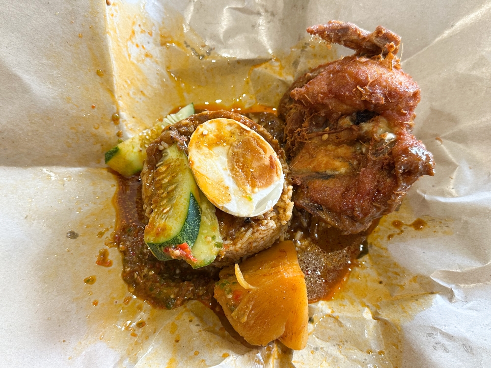 Get your hands on this parcel of goodness with 'nasi kukus', curry, 'pajeri nenas', salted egg and a juicy, crunchy 'ayam berempah goreng'. — Picture by Lee Khang Yi