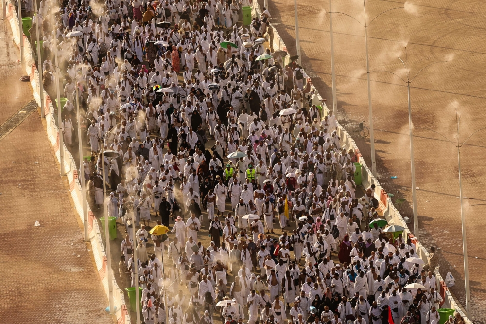 Muslim pilgrims walk under mist dispensers as they arrive to perform the symbolic 'stoning of the devil' ritual during the annual hajj pilgrimage in Mina on June 16, 2024. — AFP pic