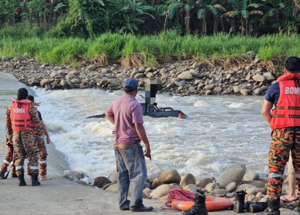 Bomba personnel get ready to rescue the man, who managed to climb on top of his vehicle’s roof. — Bomba pic