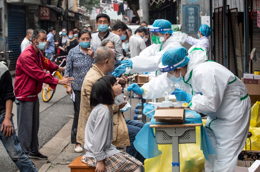 File photo of medical workers performing swab tests for Covid-19 on residents on a street in Wuhan on May 15, 2020. —  AFP