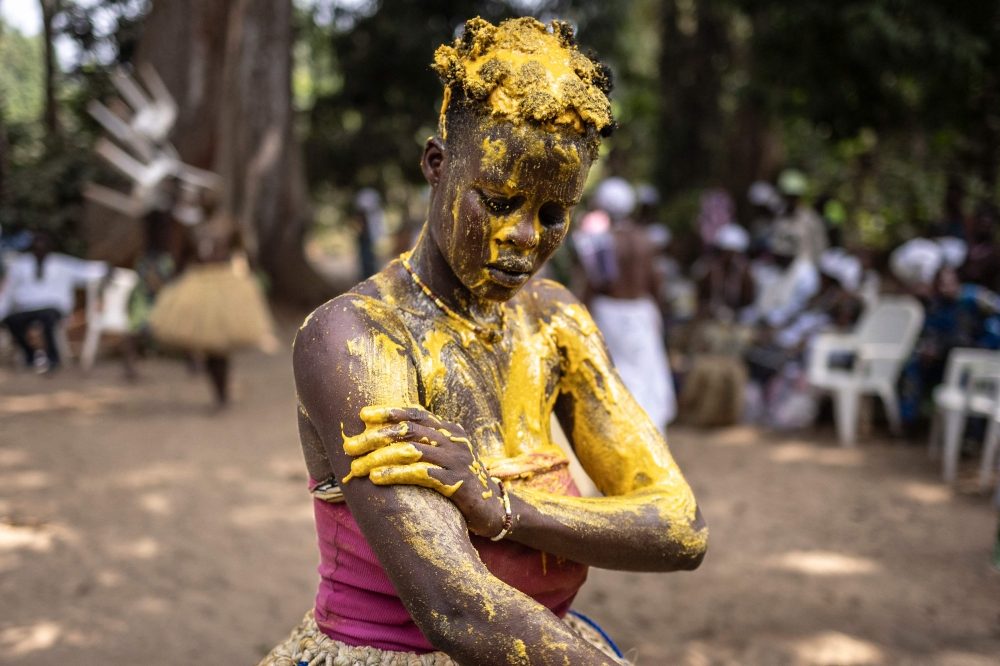 A Kokou initiate, a warrior god in the traditional religion of Benin, covers herself with a mixture of vegetable red oil mixed with maize flour in the sacred forest in Ouidah, on January 9, 2025 during the first day of the Voodoo Festival. — AFP pic