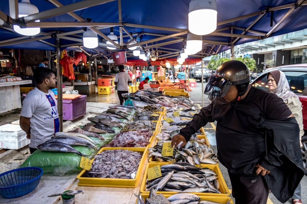 A man buys fish at the Chow Kit wet market in Kuala Lumpur October 12, 2023. — Picture by Firdaus Latif
