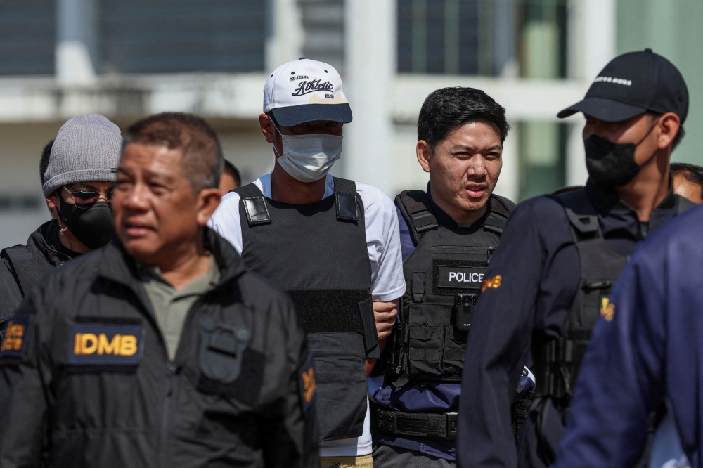 Ekkalak Paenoi, a suspect in the assassination of a former politician with now-dissolved Cambodia National Rescue Party (CNRP) Lim Kimya, 74, is escorted by police officers as he arrives in Thailand following handing over from Cambodia to Thai authorities, in Bangkok, Thailand, January 11, 2025. — Reuters pic