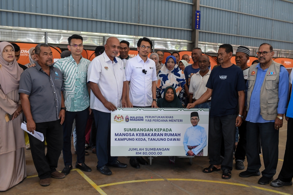 Political secretary to the finance minister, Muhammad Kamil Abdul Munim, hands over the contribution to the heads of households at the temporary relief centre at Sekolah Jenis Kebangsaan Cina (SJKC) Choong Cheng, Tanjung Dawai in Sungai Petani January 12, 2025. — Bernama pic