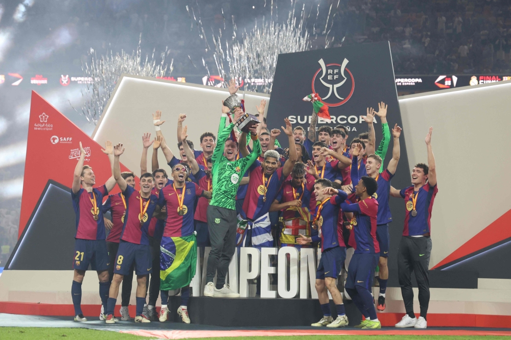 Barcelona players celebrate with the trophy after winning the Spanish Super Cup final football match against Real Madrid. — AFP pic