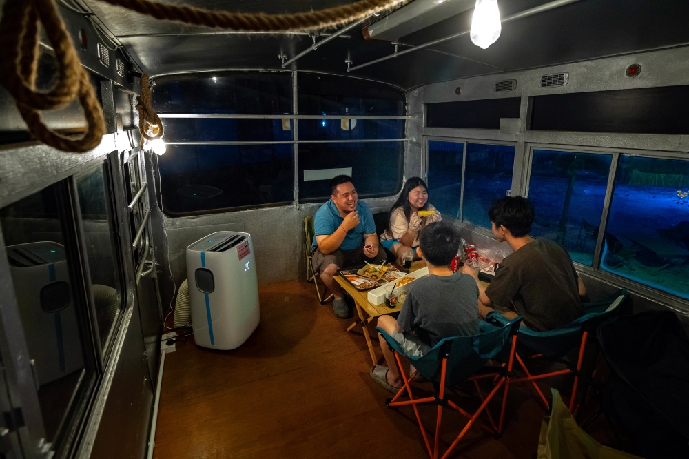 Diners enjoy their meal inside a decommissioned bus at the Boss Bus Camp in Ipoh. — Bernama pic   