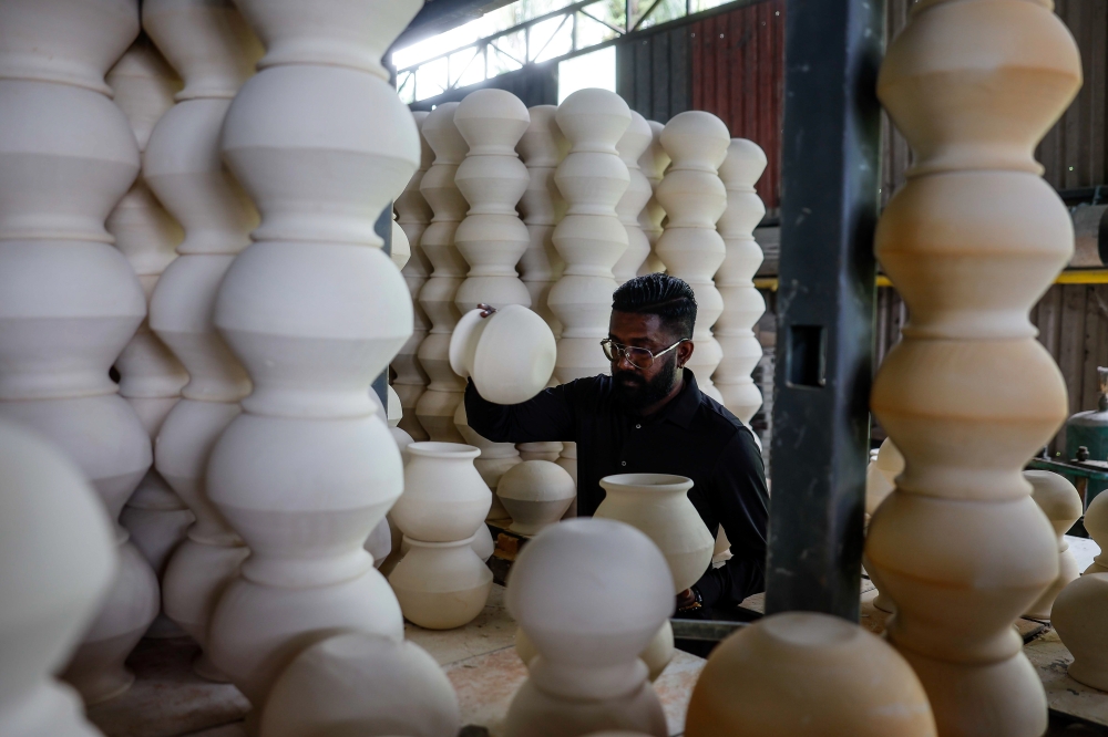 Preparing for Pongal: A. Ananth of Aru Enterprise arranges sun-dried traditional clay pots for the harvest festival, which will be celebrated by Hindus tomorrow. — Bernama pic