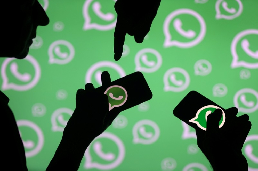 Men pose with smartphones in front of the WhatsApp logo in this illustration September 14, 2017. — Reuters pic