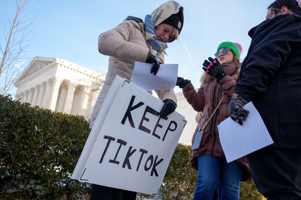 Sarah Baus holds a sign that reads 'Keep TikTok' as she and other content creators Sallye Miley and Callie Goodwin stand outside the U.S. Supreme Court Building. — AFP pic