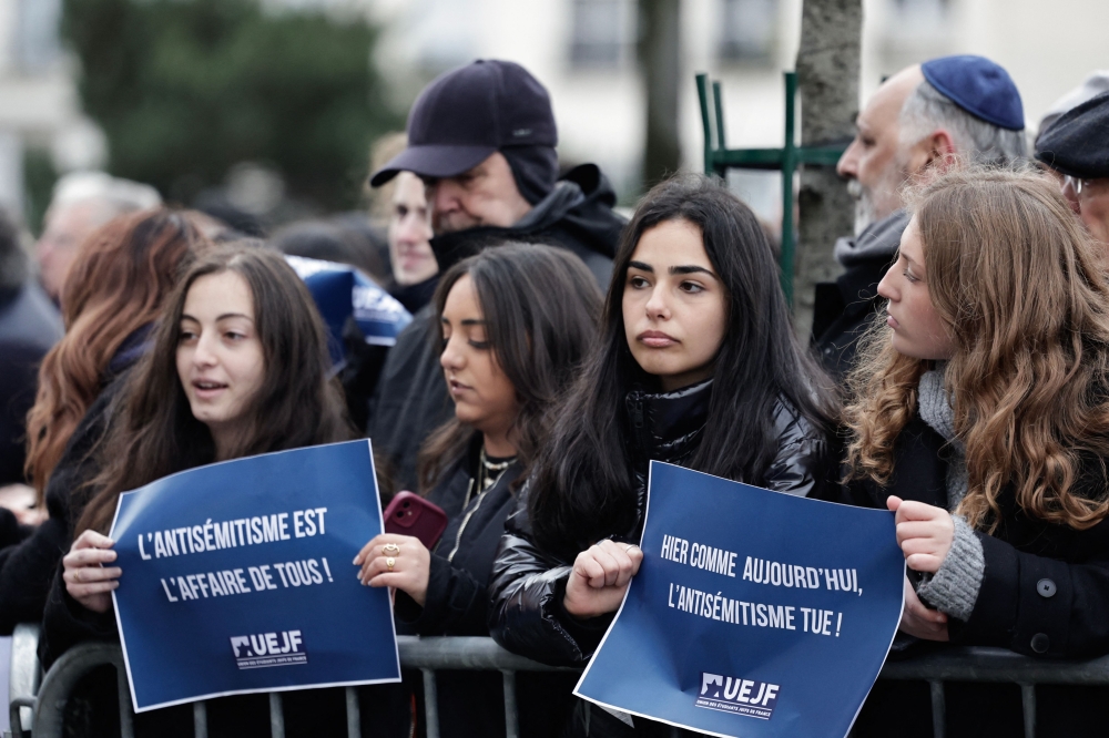 Attendees hold placards which read ‘Yesterday and today alike, antisemitism kills’ and ‘Antisemitism is everyone’s problem’ outside the Hypercacher Supermarket in Paris January 9, 2025, during a commemoration organised by the Representative Council of French Jewish Institutions (CRIF) to pay tribute to the victims and mark the 10th anniversary of an Islamist attack on the Hypercacher Jewish supermarket. — AFP pic