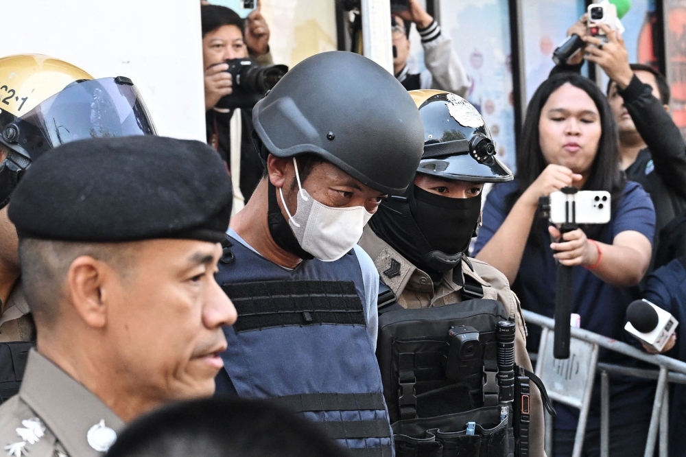 Thai national Ekalak Paenoi, a suspect in the alleged killing of former lawmaker of the dissolved Cambodia National Rescue Party (CNRP) Lim Kimya, is escorted into a police van to transport him to the Criminal Court from Chana Songkram Police Station in Bangkok January 13, 2025. — AFP pic