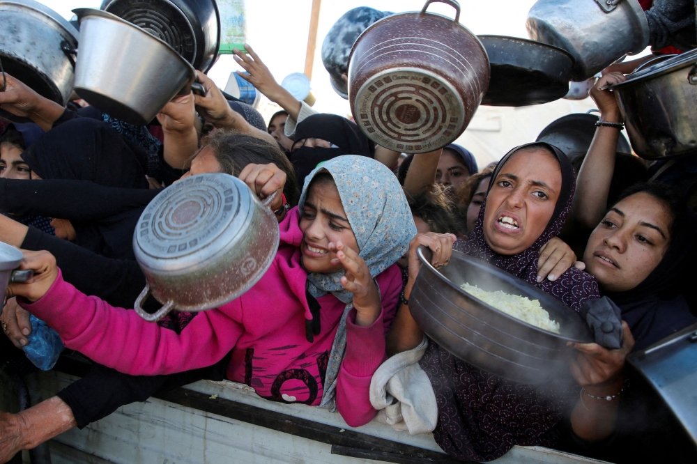 Palestinians gather to receive food cooked by a charity kitchen, amid a hunger crisis, as the Israel-Gaza conflict continues, in Khan Younis in the southern Gaza Strip, November 19, 2024. — Reuters pic