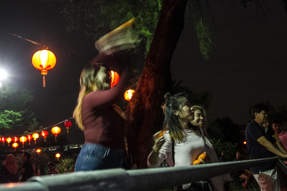 A file photograph shows people throwing mandarin oranges into Taman Tasik Jaya for the Chap Goh Meh celebrations in Petaling Jaya, Selangor. — Picture by Shafwan Zaidon