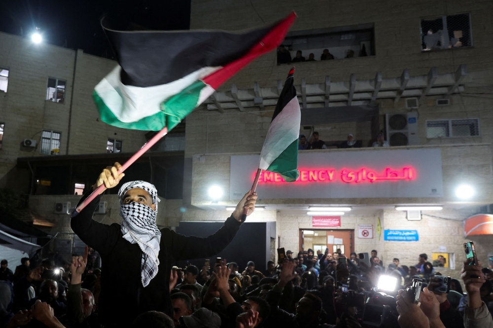 A man waves Palestinian flags as Palestinians react to news on a ceasefire deal with Israel, in Deir Al-Balah in the central Gaza Strip, January 15, 2025. — Reuters pic