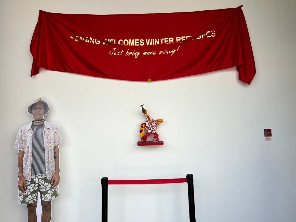 The red cloth with the gold words art titled ‘Not too soft language’ at the entrance to the exhibition and below it a sculpture titled ‘cultural desert, no one understands the hero’. A large real-sized print of bibichun is placed next to it. — Picture by Opalyn Mok 