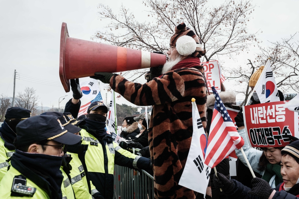 A supporter of detained and impeached South Korean President Yoon Suk-yeol holds up a safety cone during a rally at the entrance of the Seoul Detention Centre in Seoul January 16, 2025. — AFP pic