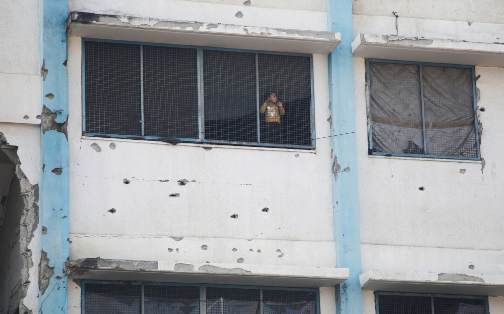 A displaced Palestinian child looks out from a window at a school being used as a shelter, ahead of a ceasefire between Israel and Hamas, set to take effect on Sunday, in Khan Younis in the southern Gaza Strip January 16, 2025. — Reuters pic