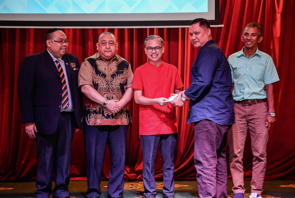 Communications Minister Fahmi Fadzil (centre) presented a contribution to former athlete Haris Fadzillah Osman (2nd right) at the Appreciation Tea Reception and Contribution Presentation Ceremony for Former National Cycling Athletes in conjunction with the 50th Anniversary Federal Territories Friendly Charity Ride held at the Royal Selangor Club January 18, 2025. Also present were Organising Committee Advisor Dato Zulkifly Ibrahim (second from left) and Royal Selangor Club President Rizal Edi Effendi (left). — Bernama pic