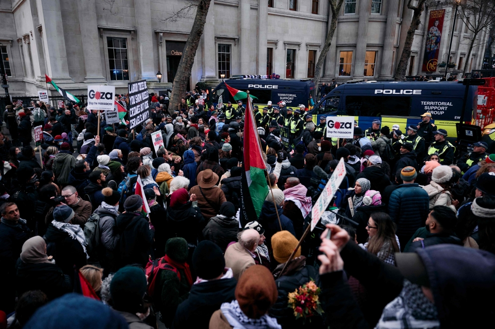 Protesters holding placards and flags face a line of police at Trafalgar Square in central London at a National demonstration for Palestine. — AFP pic
