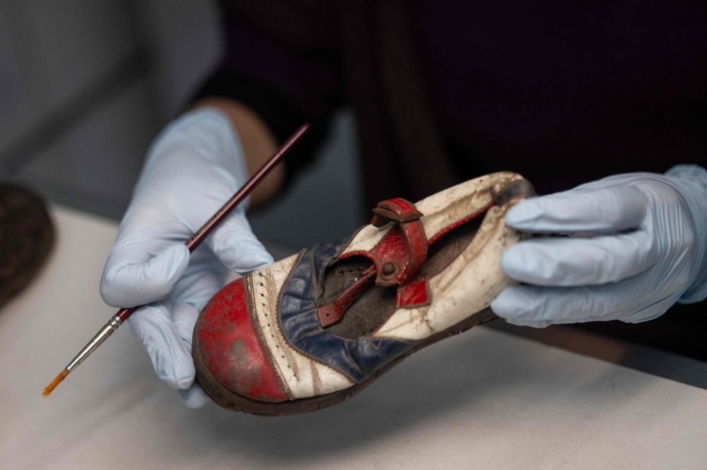 A volunteer at the conservation laboratory on the grounds of the Memorial And Museum Auschwitz-Birkenau, a former German Nazi concentration and extermination camp, works on the preservation of a shoe that belonged to a child – a victim of the camp, in Oswiecim, Poland, on January 14, 2025. — AFP pic