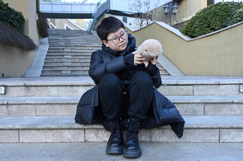 Zhang Yachun playing with her AI-powered robot named Aluo at a shopping centre in Beijing. — AFP pic
