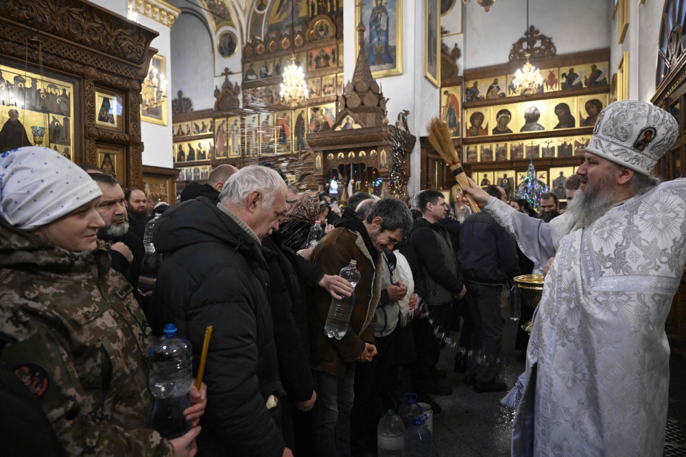 A priest blesses believers during the Epiphany celebration in the Sviatogirsk Monastery in the town of Svyatogirsk, Donetsk region, on January 19, 2025, amid the Russian invasion of Ukraine. Orthodox Church of Ukraine has moved to the new religious calendar but some Ukrainians, including followers of the Ukrainian Orthodox Church, still celebrate the epiphany on January 19. — AFP pic 