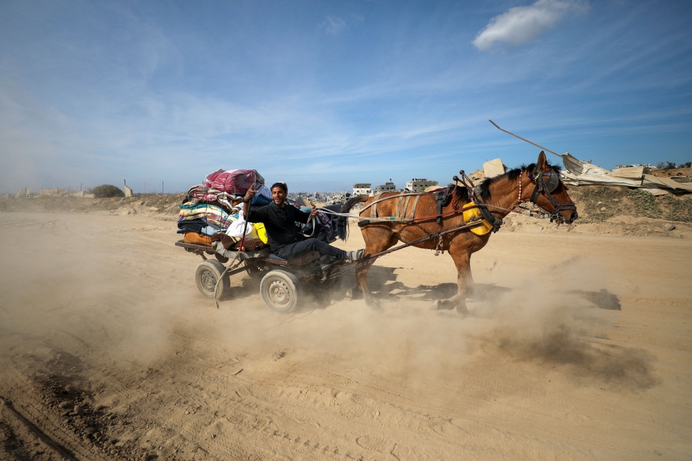 A Palestinian man reacts while riding a horse-drawn cart as he returns to his devastated neighbourhood, following a ceasefire between Israel and Hamas, in Jabalia in the northern Gaza Strip, January 19, 2025. — Reuters pic 
