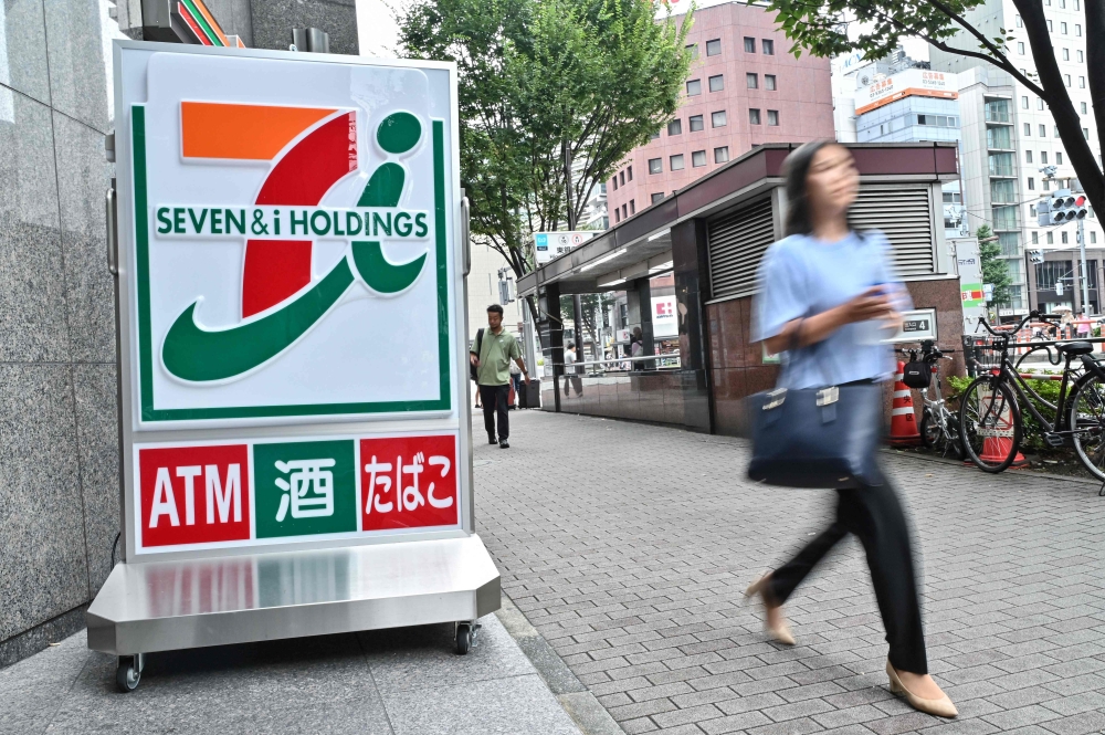 File picture of a woman walking out of a 7-Eleven convenience store along a street in central Tokyo on August 22, 2024. Seven Bank’s president and representative director Masaaki Matsuhashi said the company also plans to expand to more areas in 2026, covering Sabah, Sarawak and selected suburban areas throughout Malaysia. — AFP pic