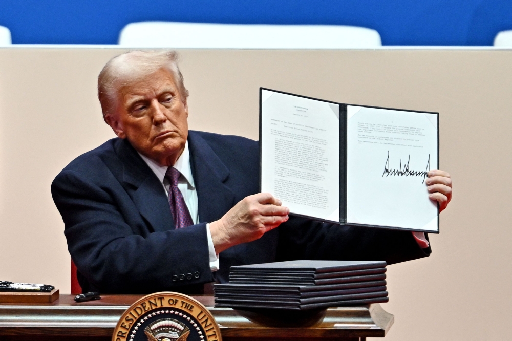 Donald Trump signs executive orders during the inaugural parade inside Capital One Arena, in Washington. — Pic by AFP