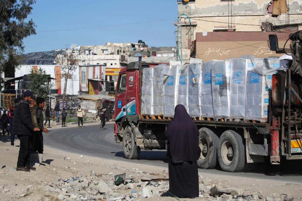 Palestinians watch a truck loaded with aid drive by in Gaza’s southern city of Rafah. — Pic by AFP