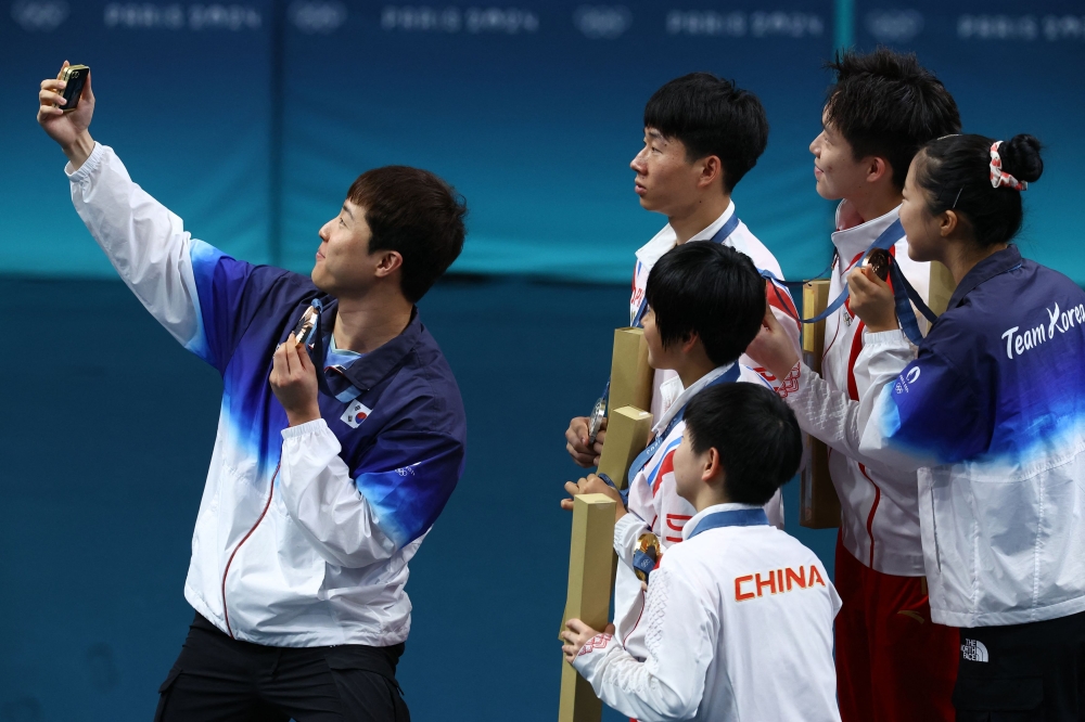 South Korea’s Lim Jong-hoon takes a selfie with North Korea’s Ri Jong Sik and Kim Kum Yong, the South’s Shin Yu-bin and the victorious Chinese team Wang Chuqin and Sun Yingsha as they pose with their Olympic medal last year. — Reuters pic
