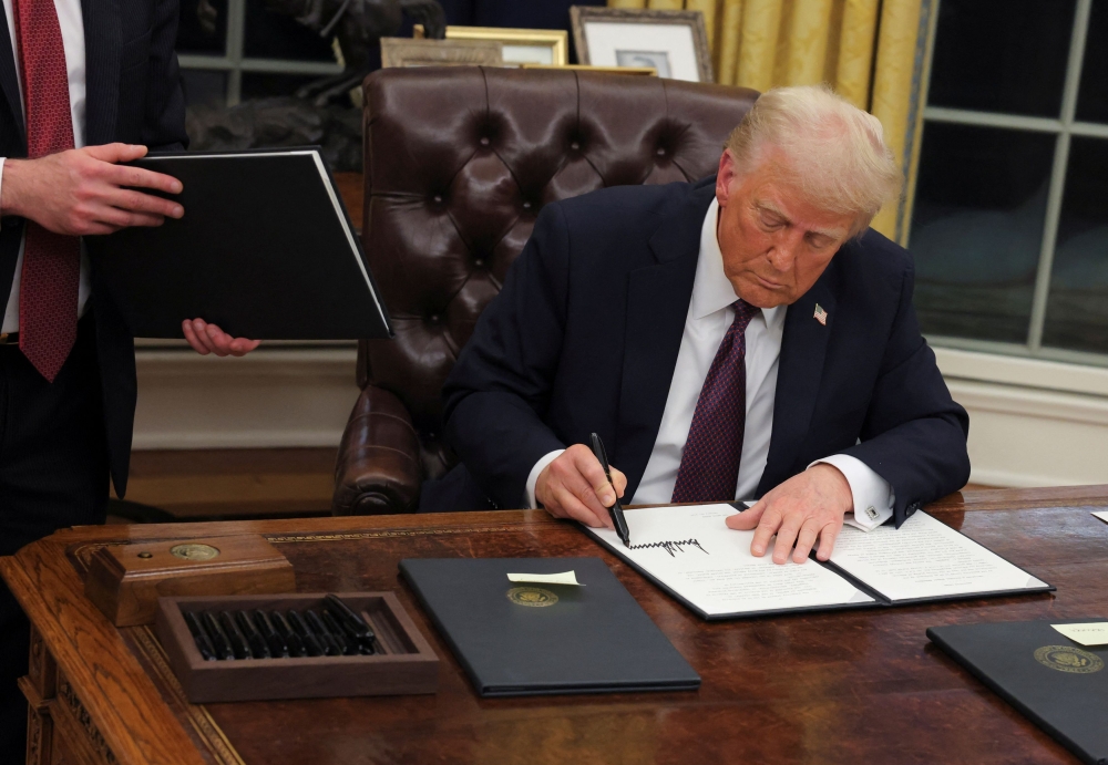 US President Donald Trump signs documents as he issues executive orders and pardons for January six defendants in the Oval Office at the White House on Inauguration Day in Washington, January 20, 2025. — Reuters pic 