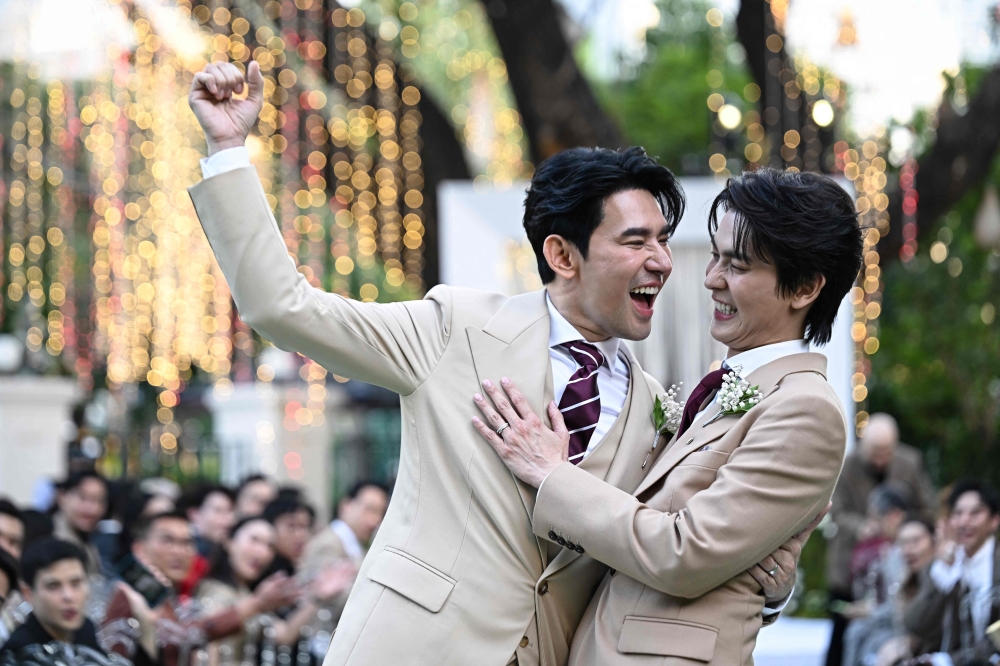 This photo taken on January 10, 2025 shows Apiwat ‘Porsch’ Apiwatsayree (left) and Sappanyoo ‘Arm’ Panatkool posing for photos at their unofficial wedding ceremony in Bangkok. — AFP pic